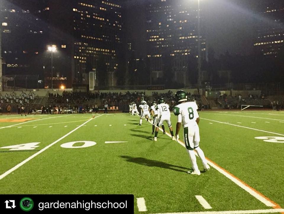 NMSS players on Gardena High football team line up on field under bright lights.