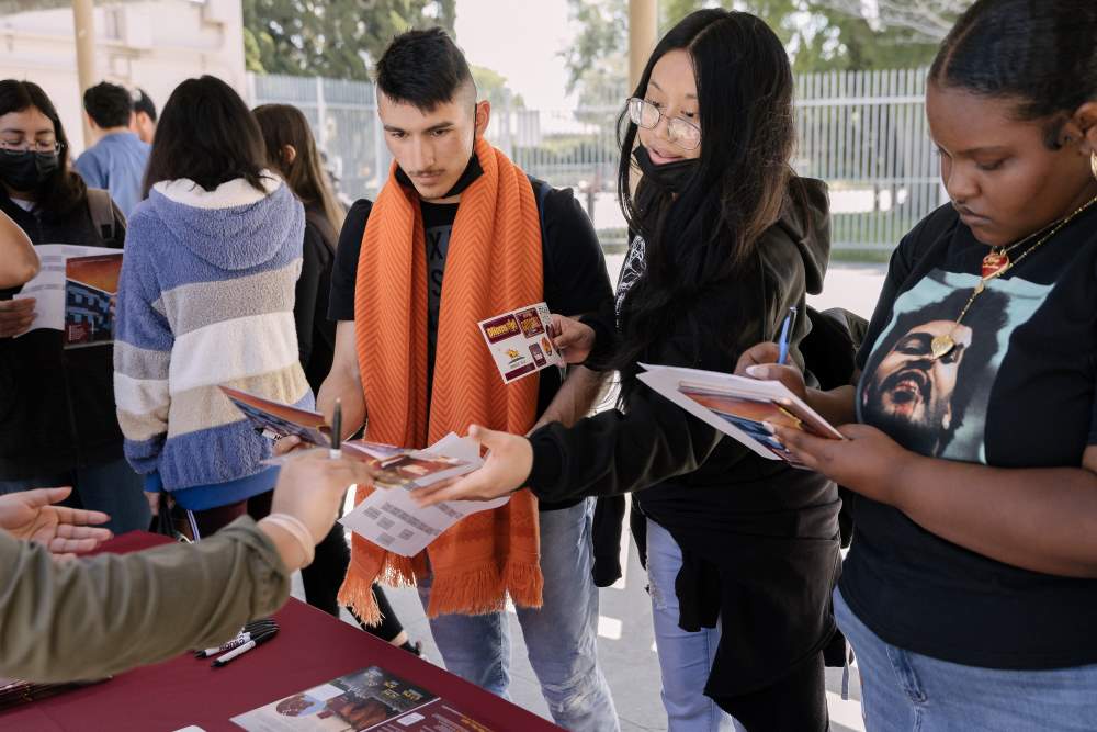 NMSS students at a College Fair table gather materials and fill out forms.